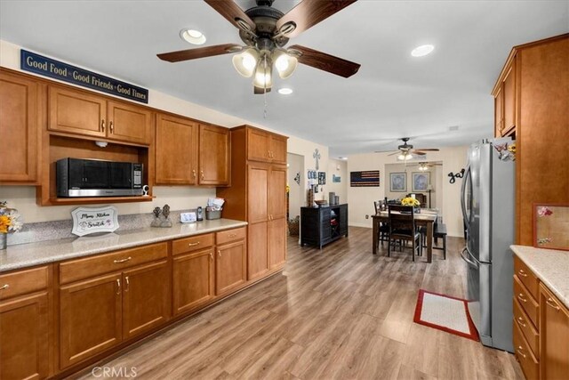 kitchen featuring ceiling fan, stainless steel appliances, and light wood-type flooring