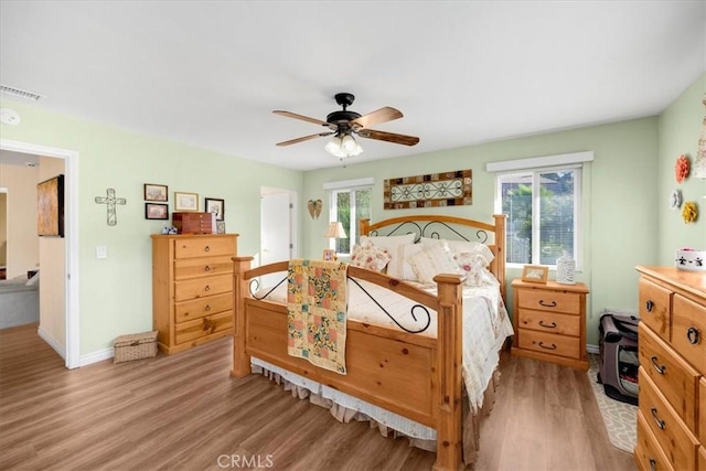 bedroom with multiple windows, light hardwood / wood-style floors, and ceiling fan