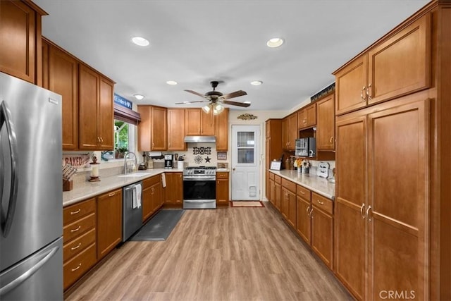 kitchen featuring stainless steel appliances, sink, ceiling fan, and light hardwood / wood-style flooring