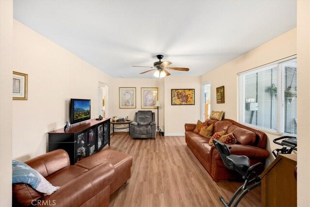 living room with light wood finished floors, ceiling fan, and baseboards