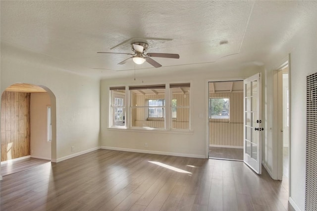 empty room featuring ceiling fan, dark wood-type flooring, and a textured ceiling