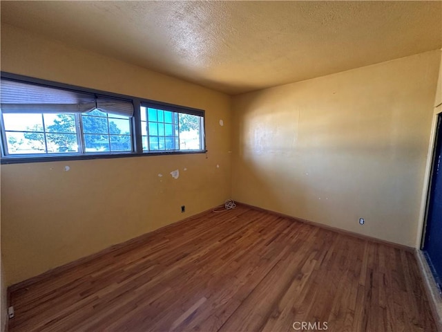 unfurnished room featuring hardwood / wood-style floors and a textured ceiling