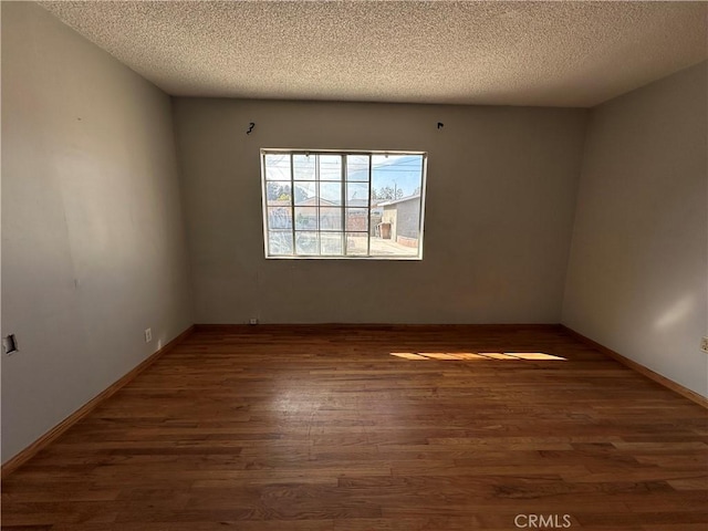 spare room with dark wood-type flooring and a textured ceiling