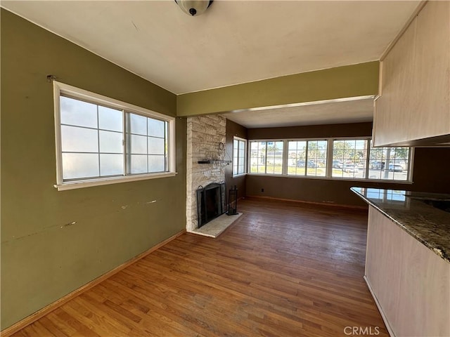 unfurnished living room featuring a stone fireplace and dark wood-type flooring