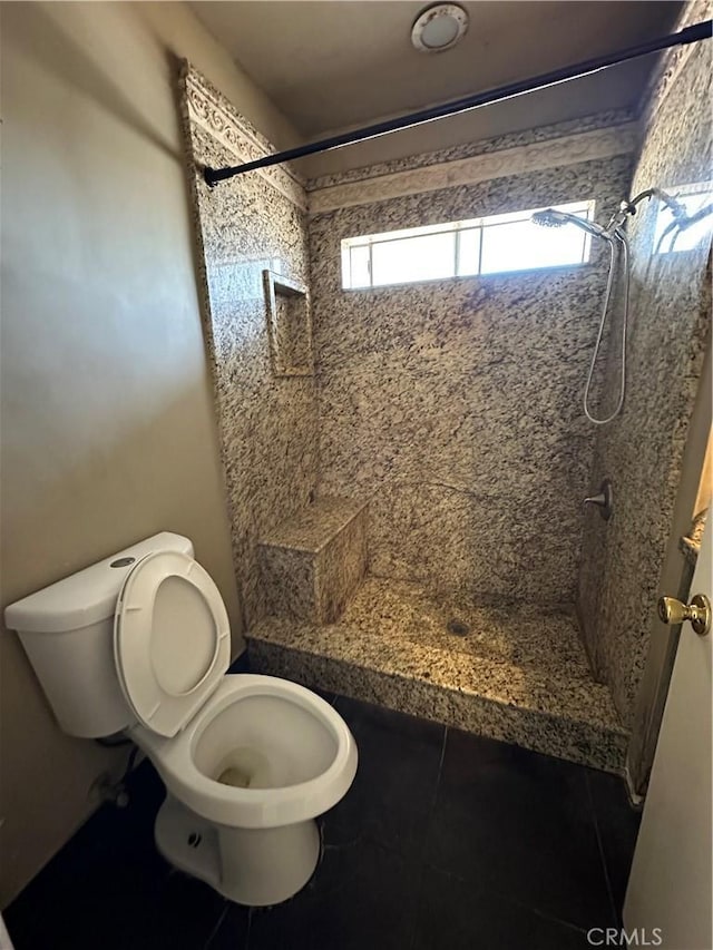 bathroom featuring tiled shower and toilet