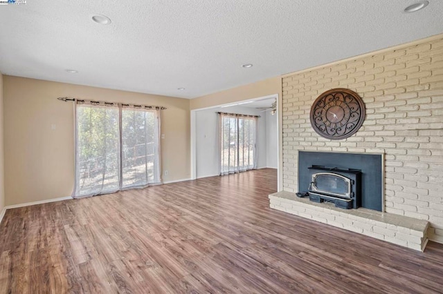 unfurnished living room with hardwood / wood-style floors, a textured ceiling, and a wood stove