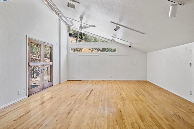 unfurnished room with vaulted ceiling, ceiling fan, light hardwood / wood-style floors, a healthy amount of sunlight, and track lighting