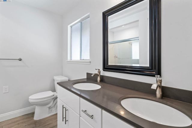 bathroom featuring walk in shower, vanity, toilet, and hardwood / wood-style floors