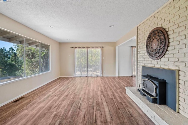 unfurnished living room featuring hardwood / wood-style floors, a textured ceiling, and a wood stove