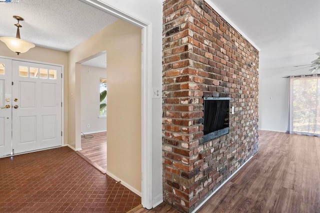 entryway featuring ceiling fan, dark hardwood / wood-style floors, a textured ceiling, and a fireplace