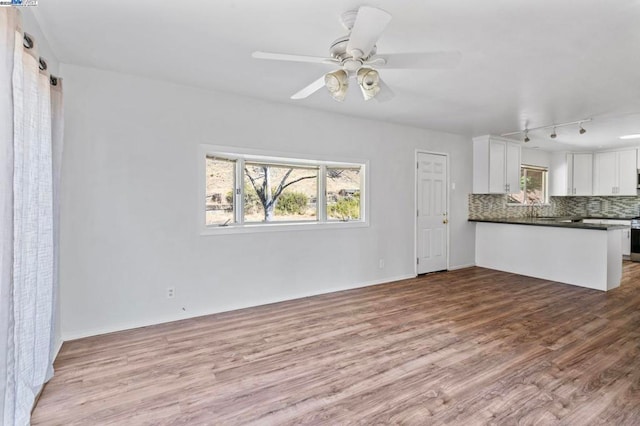 unfurnished living room featuring ceiling fan and light wood-type flooring