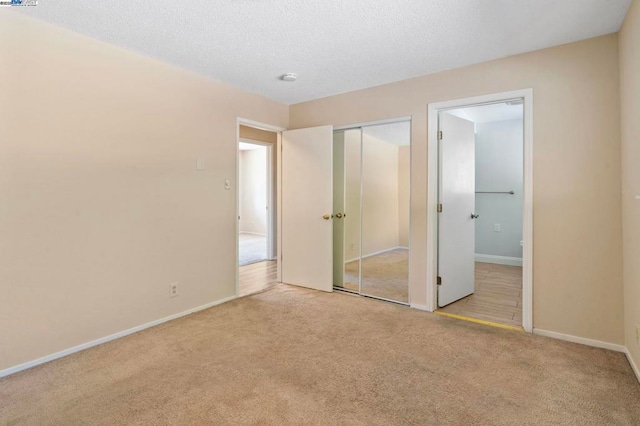 unfurnished bedroom featuring light colored carpet, a textured ceiling, and a closet