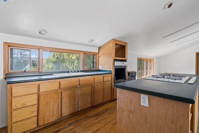 kitchen featuring sink, dark wood-type flooring, a center island, vaulted ceiling, and oven