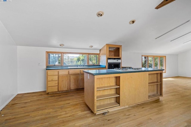 kitchen with sink, stainless steel oven, white gas cooktop, light wood-type flooring, and a kitchen island