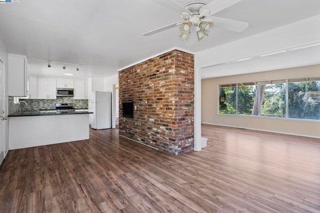 unfurnished living room featuring dark wood-type flooring and ceiling fan