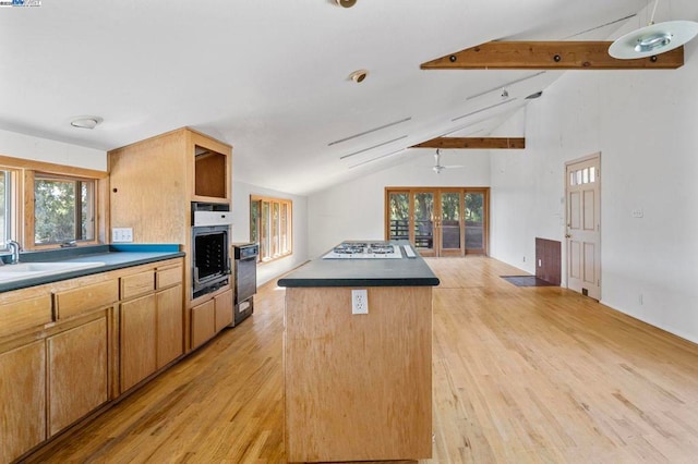 kitchen with wall oven, sink, lofted ceiling with beams, and a center island