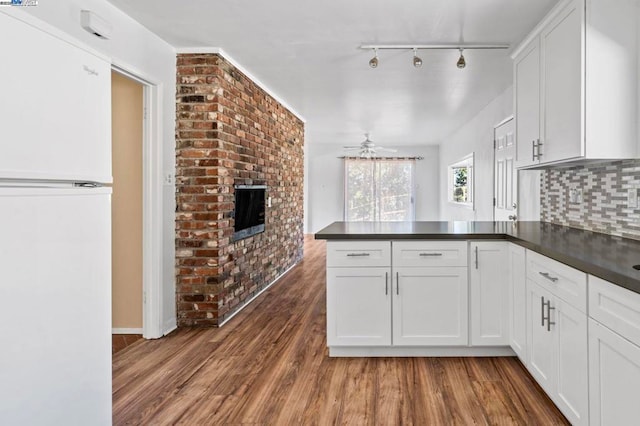 kitchen featuring white cabinetry, wood-type flooring, backsplash, white fridge, and kitchen peninsula