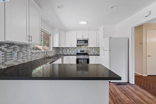 kitchen with sink, kitchen peninsula, white cabinets, and appliances with stainless steel finishes