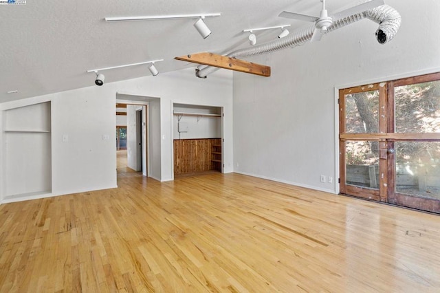 unfurnished living room featuring vaulted ceiling, rail lighting, ceiling fan, and light wood-type flooring