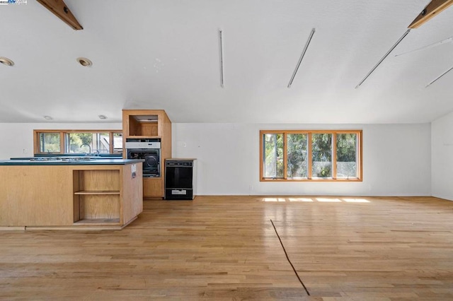 kitchen with plenty of natural light, oven, light wood-type flooring, and light brown cabinets