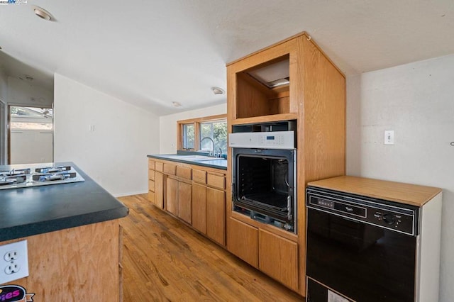 kitchen featuring sink, black dishwasher, wall oven, stainless steel gas stovetop, and light wood-type flooring