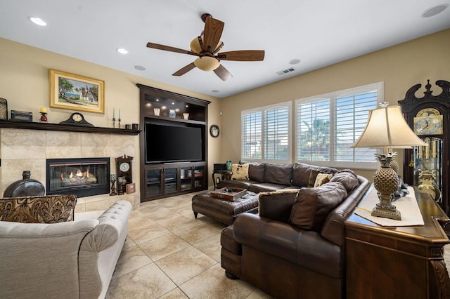 tiled living room featuring a tiled fireplace and ceiling fan