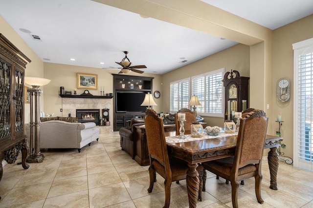 tiled dining area featuring ceiling fan and a fireplace