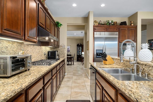 kitchen featuring stainless steel appliances, tasteful backsplash, sink, and light stone counters