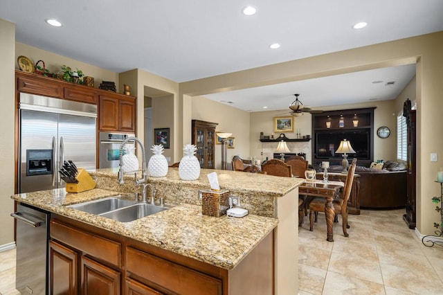 kitchen featuring light stone counters, sink, an island with sink, and appliances with stainless steel finishes