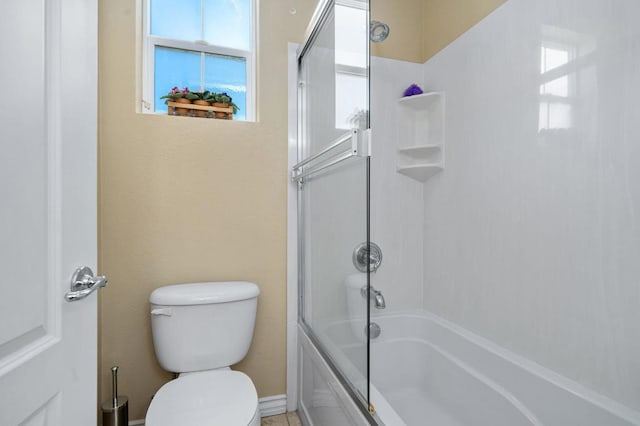 bathroom with toilet and shower / bath combination with glass door