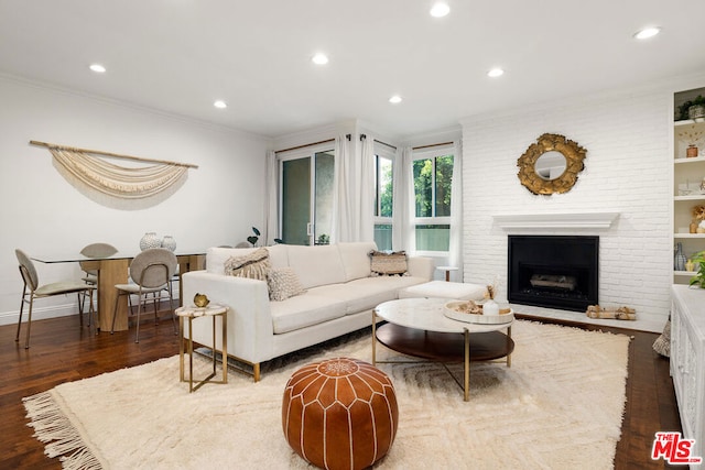 living room with dark hardwood / wood-style flooring, crown molding, and a fireplace