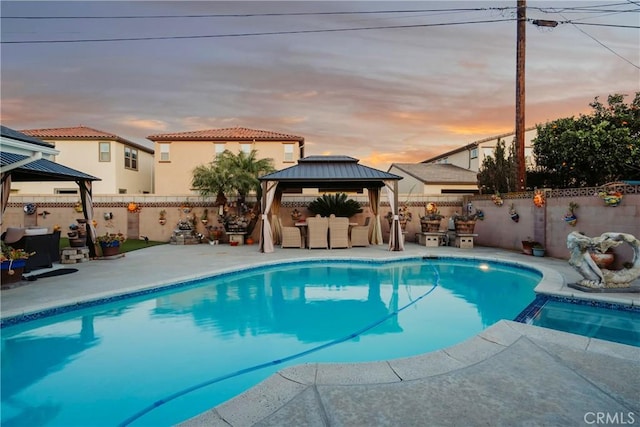 pool at dusk with a gazebo and a patio