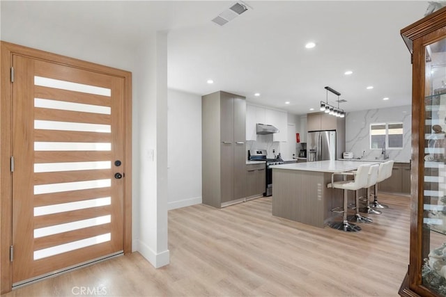 kitchen with pendant lighting, a breakfast bar, white cabinetry, stainless steel appliances, and a center island