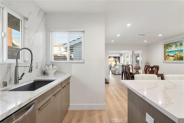 kitchen with sink, a wealth of natural light, and light stone counters