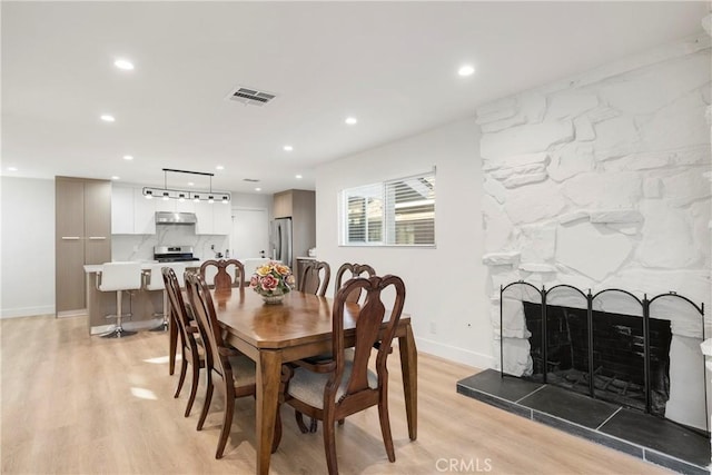 dining area featuring a fireplace and light hardwood / wood-style flooring