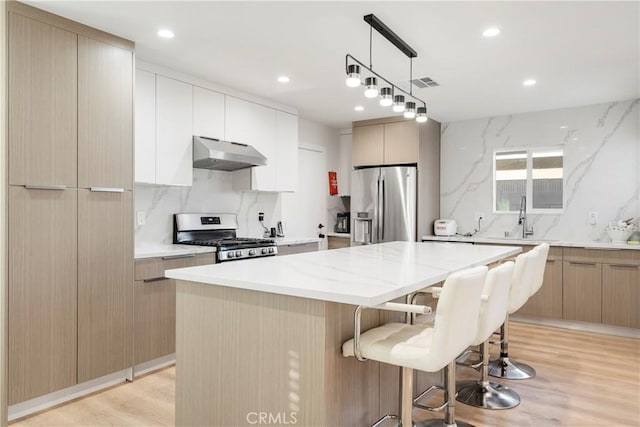 kitchen with sink, stainless steel appliances, a center island, and light wood-type flooring