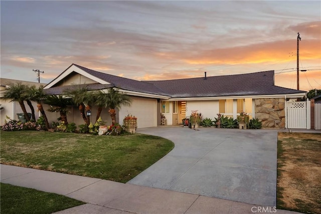 ranch-style home featuring a garage and a lawn