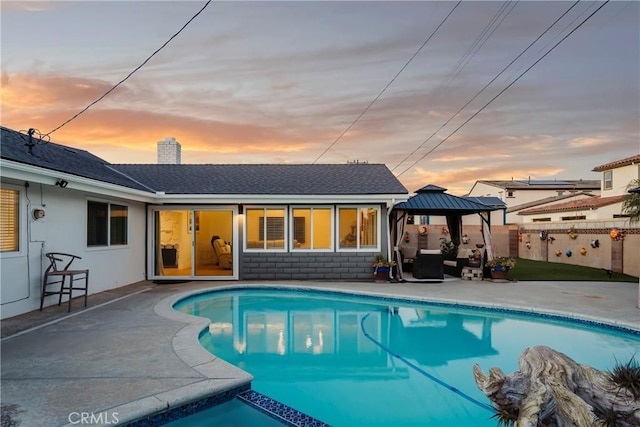 pool at dusk featuring a gazebo and a patio area