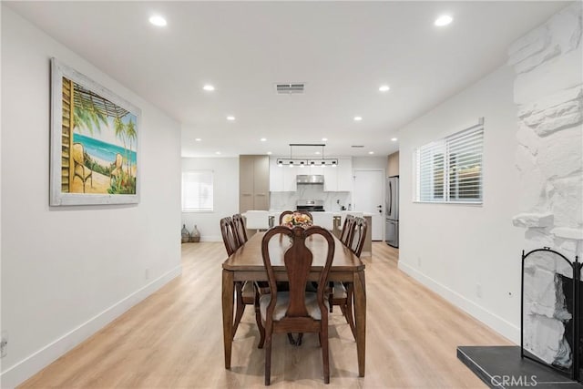 dining area with a large fireplace and light hardwood / wood-style flooring