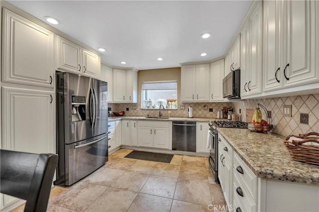 kitchen featuring tasteful backsplash, sink, stainless steel appliances, and white cabinets