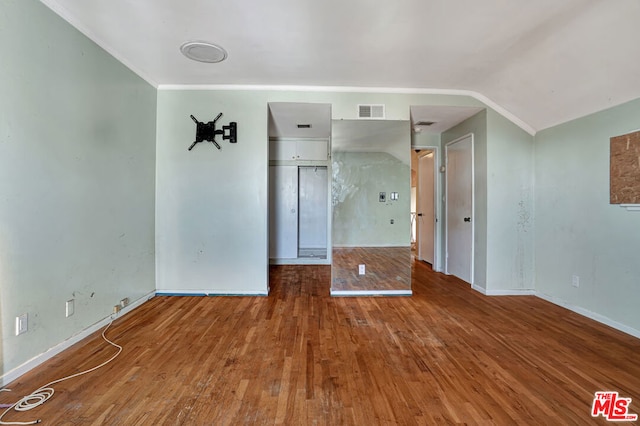 spare room featuring lofted ceiling, hardwood / wood-style flooring, and crown molding