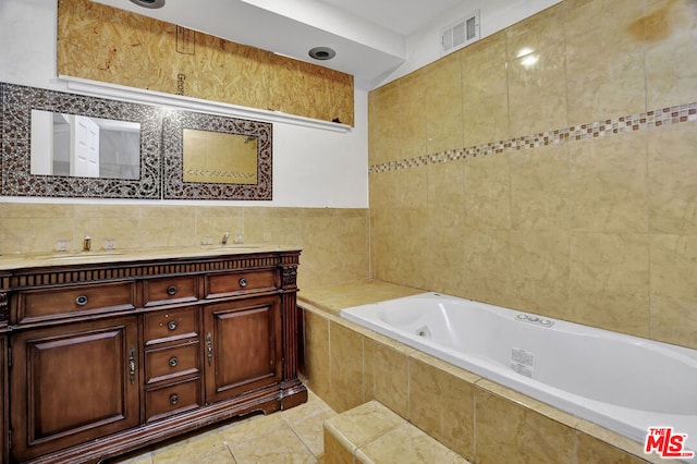 bathroom featuring a relaxing tiled tub, vanity, tile patterned flooring, and tile walls