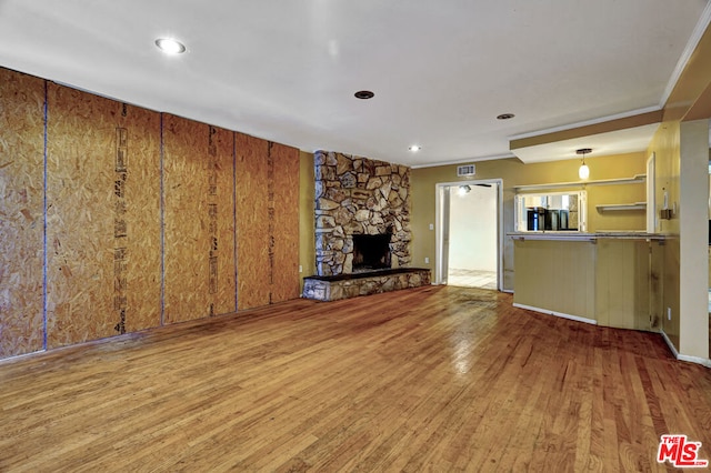 unfurnished living room featuring hardwood / wood-style flooring, a fireplace, and ornamental molding