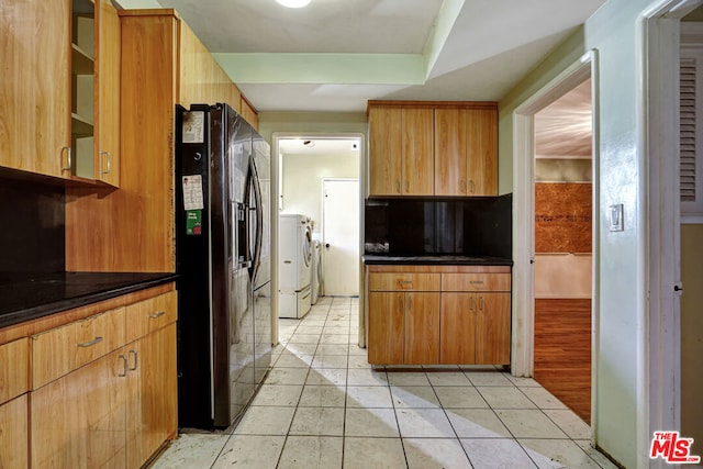 kitchen with tasteful backsplash, light tile patterned floors, independent washer and dryer, and black refrigerator with ice dispenser