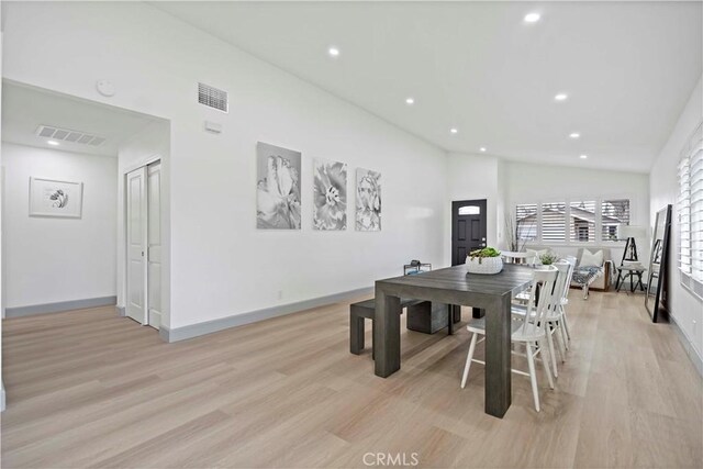 dining area featuring high vaulted ceiling and light wood-type flooring