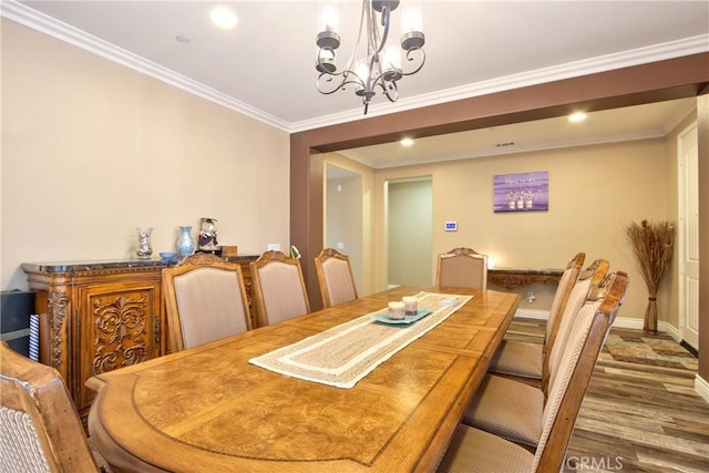 dining area with hardwood / wood-style flooring, ornamental molding, and a chandelier