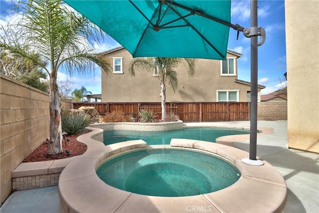 view of pool with a pool with connected hot tub, a fenced backyard, and a patio