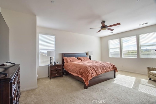 bedroom featuring multiple windows, light carpet, and ceiling fan