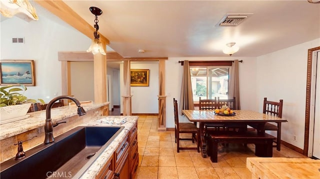 kitchen with pendant lighting, light stone countertops, and sink