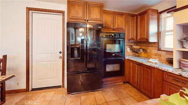 kitchen featuring tasteful backsplash, light stone countertops, and black appliances